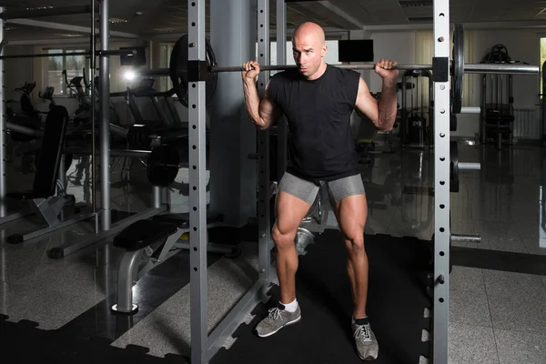 Fitness Man Usando Barbell Ejercicio de piernas dentro del gimnasio — Foto de Stock