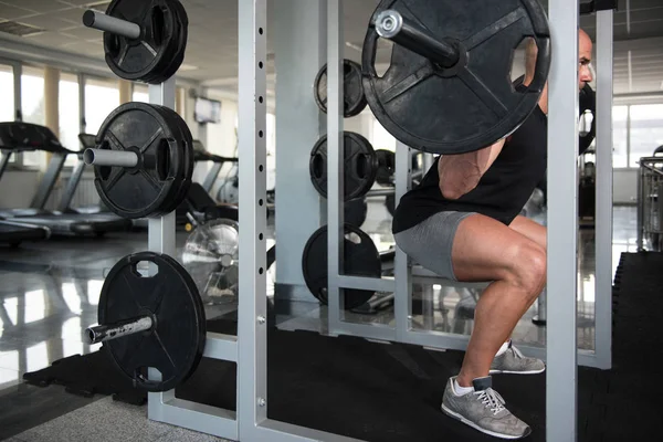 Fitness Man använder skivstång tränar ben inuti Gym — Stockfoto