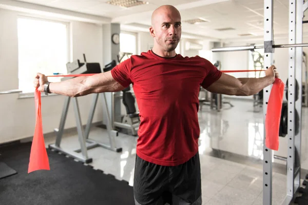 Culturista maschio che esercita in palestra con la banda di resistenza — Foto Stock