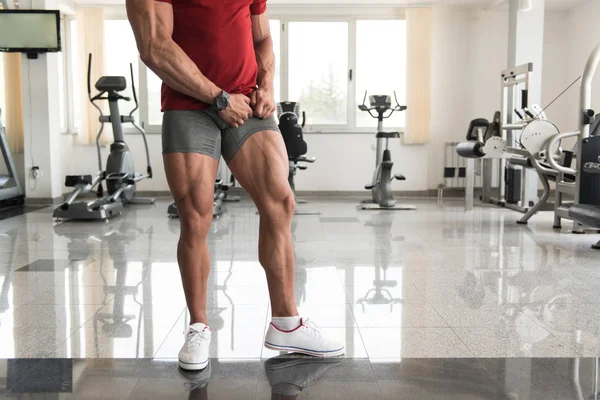 Człowiek w siłowni pokazuje nogi dobrze wyszkolonych — Zdjęcie stockowe