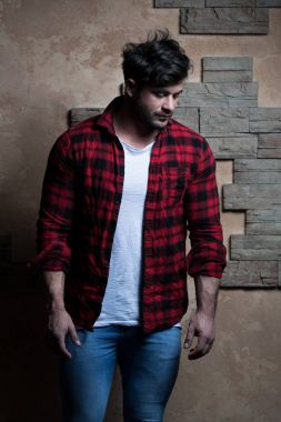 Tuğla arka plan üzerinde ayakta kot tişörtlü adam