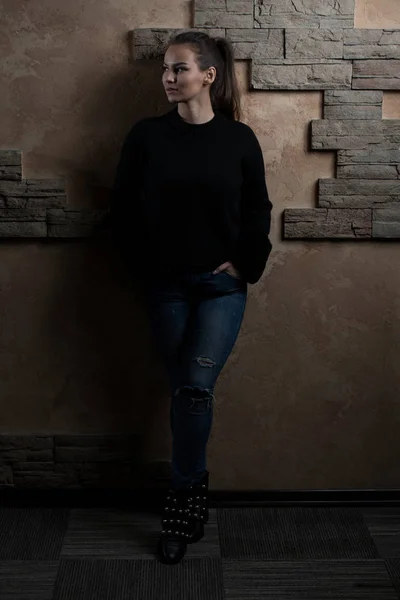 Женщина стоит спиной к кирпичной стене — стоковое фото