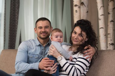 Mutlu Aile Baba ve Anne Kanepede Bir Bebekle Oynuyor