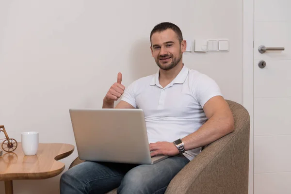 一个英俊的男人坐在客厅的桌子上 在家里用笔记本电脑 — 图库照片