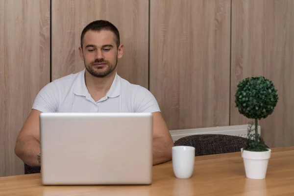 有信心的商人在家里 他正在客厅里喝咖啡休息 还在用笔记本电脑与人交流 — 图库照片