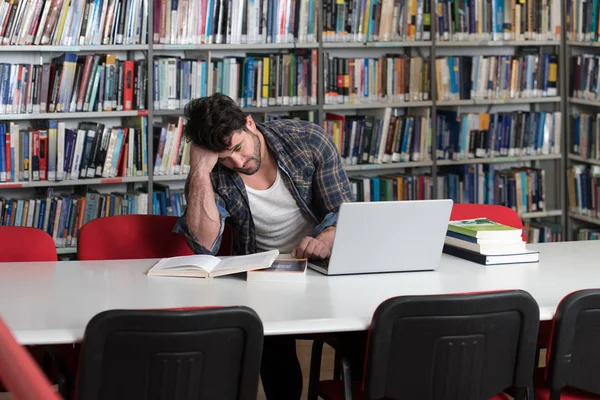 Estudiante masculino confundido leyendo muchos libros para el examen —  Fotos de Stock