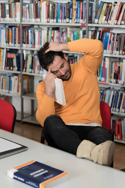 Étudiant ennuyé avec des livres à la bibliothèque — Photo