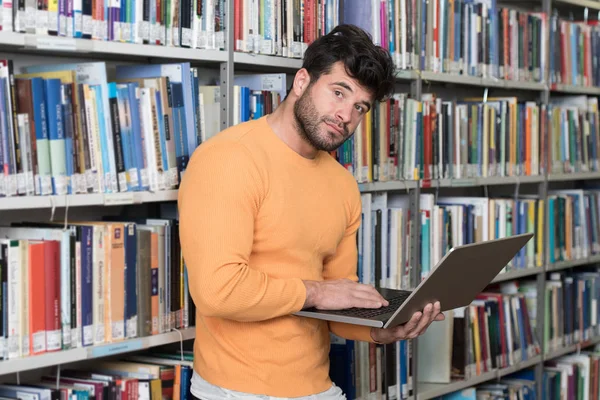 Estudante universitário bonito em uma biblioteca — Fotografia de Stock