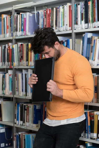 Yorgun öğrenci dizüstü bilgisayar kitaplığı ile çalışma — Stok fotoğraf