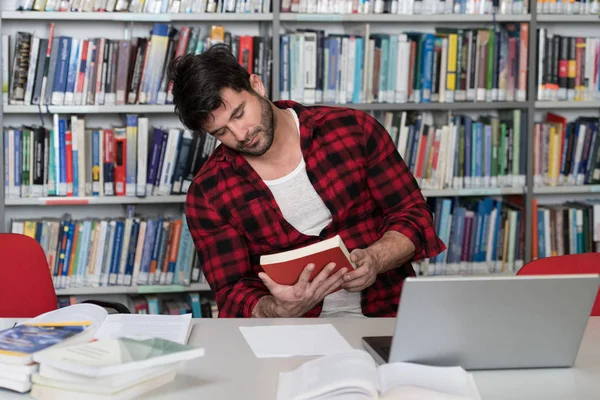 Bello studente universitario in una biblioteca — Foto Stock