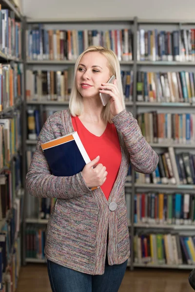 Estudiante hablando por teléfono en la biblioteca —  Fotos de Stock