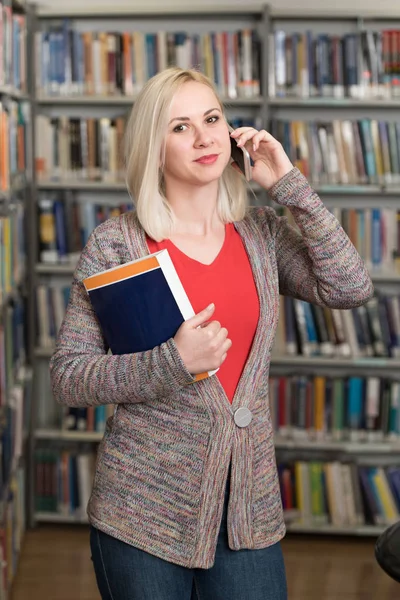 Estudiante hablando por teléfono en la biblioteca —  Fotos de Stock
