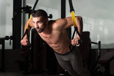 Trx Fitness askıları ile genç çekici adam eğitim