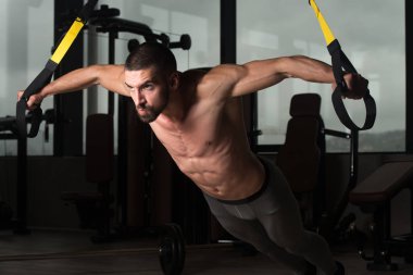 Trx Fitness askıları ile genç çekici adam eğitim