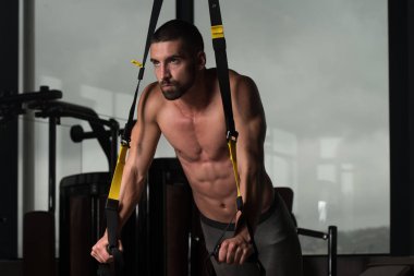 Trx Fitness askıları ile genç çekici adam eğitim