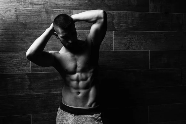 Model Flexing Muscles Against the Wall — Stock Photo, Image