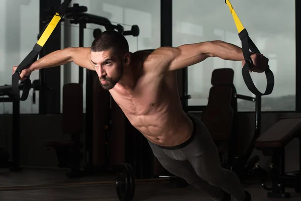 Giovane attraente uomo formazione con cinghie di fitness Trx — Foto Stock