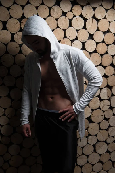 Modell som flexar muskler i Hoodie nära väggen — Stockfoto