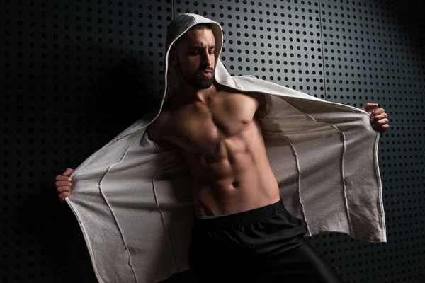 Modèle Flexing Muscles à capuche près du mur — Photo