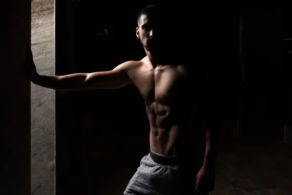 Retrato del hombre en forma en la habitación oscura —  Fotos de Stock