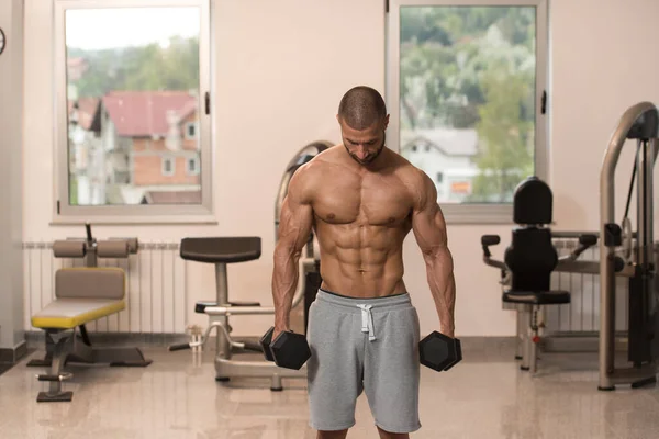 Biceps exercice avec haltères dans une salle de gym — Photo