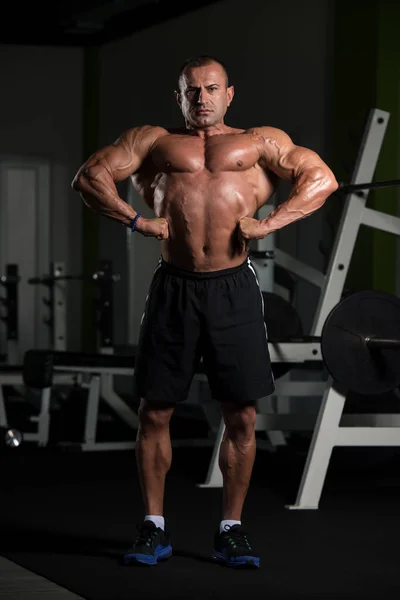 Dojrzałe muskularne człowiek Flexing mięśnie w siłowni — Zdjęcie stockowe
