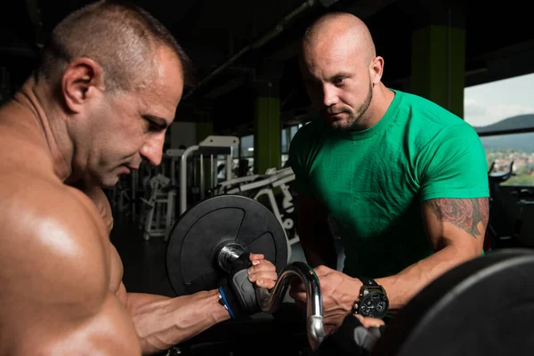 Man tåg Biceps på maskin med personlig tränare — Stockfoto