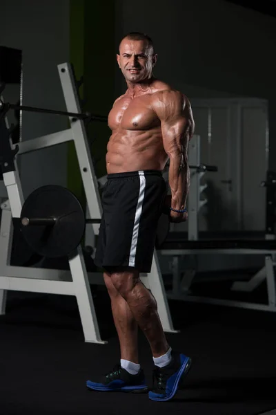 Muskulöser reifer Mann lässt Muskeln im Fitnessstudio spielen — Stockfoto