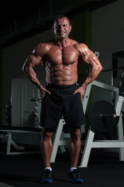 Muscular maduro hombre flexing músculos en gimnasio —  Fotos de Stock