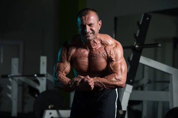 Starší svalnatý muž pružné svaly v tělocvičně — Stock fotografie
