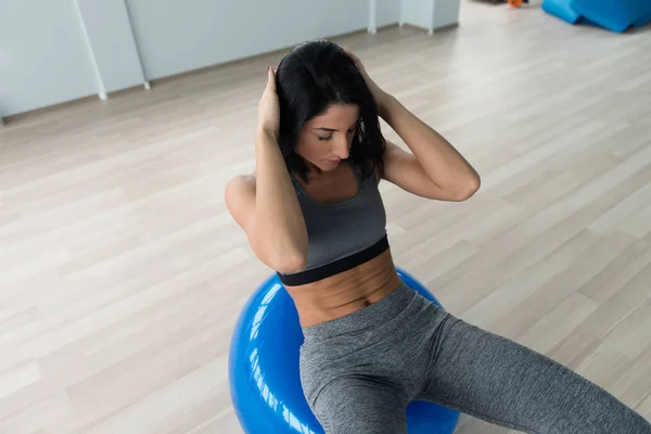 Mujer joven haciendo ejercicio abdominal en la bola —  Fotos de Stock