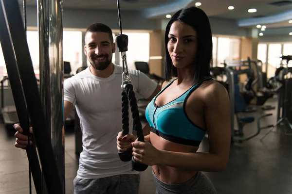 Mujer con entrenador personal en tríceps en el gimnasio —  Fotos de Stock