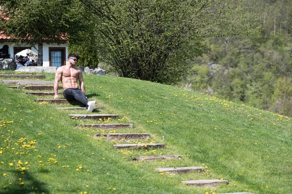 Modelo Flexing músculos ao ar livre na natureza — Fotografia de Stock