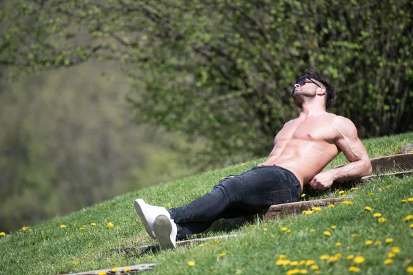 Grave modello muscolare sdraiato all'aperto in natura — Foto Stock