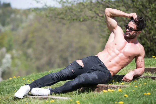 Uomo sdraiato forte all'aperto nella natura in posa — Foto Stock