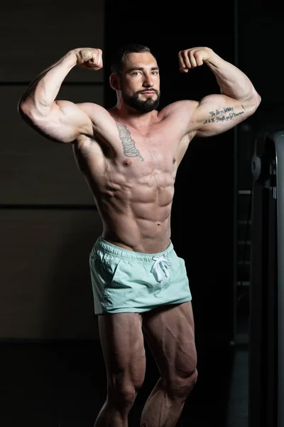 Hombres musculares está golpeando trasero doble bíceps Pose — Foto de Stock