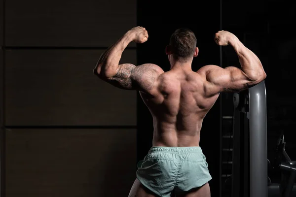 Fisiculturista executando a dose traseira de bíceps duplos — Fotografia de Stock