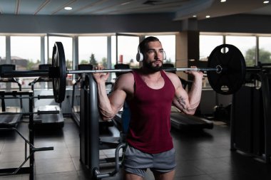 Fitness spor salonu içinde bacaklar egzersiz halter kullanan adam