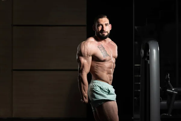 Uomo muscolare che flette i muscoli in palestra — Foto Stock