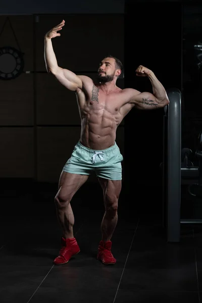 Biceps pose d'un jeune homme dans la salle de gym — Photo