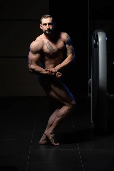 Homem muscular flexionando músculos no ginásio — Fotografia de Stock