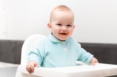 Yüksek sandalyede oturan sevimli beyaz çocuk portresi.