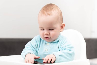 Bebek Sandalyede ve Cep telefonuyla oynuyor