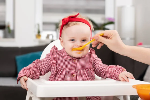 자매가 집에서 음식을 한입먹어 치우는 아기를 어머니 — 스톡 사진