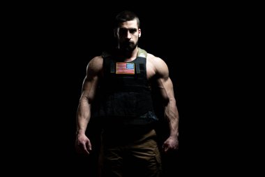 Kurşun geçirmez yelekli asker portresi ve siyah arka planda Amerikan bayrağı.