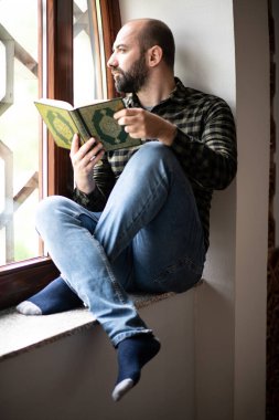 Sakallı Müslüman adam Kuran okuyor.