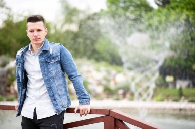 Park 'ın dışında mavi ceketli başarılı ve kendinden emin bir gencin portresi.