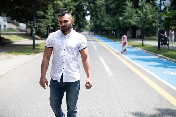 一个穿着白衬衫 自信而又成功的年轻人在公园走在外面的画像 — 图库照片