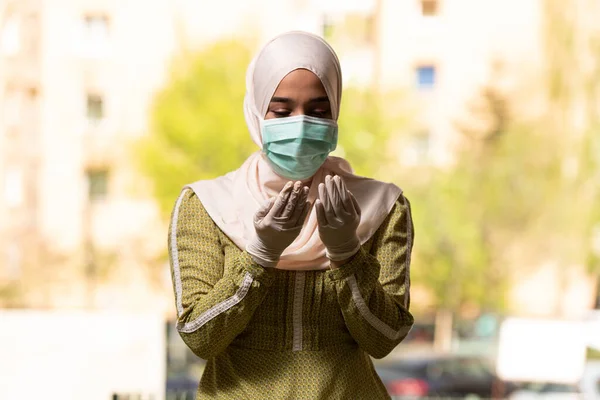 Young Muslim Woman Praying Outdoors Wearing Protective Mask and Gloves
