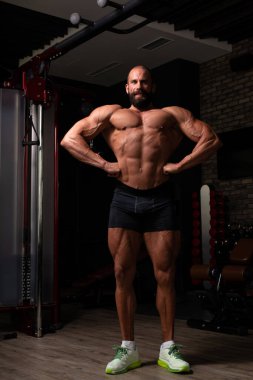 İyi eğitilmiş vücudunu gösteren genç bir adamın portresi - kaslı atletik vücut geliştirici spor sonrası vücut geliştirme modelliği pozu